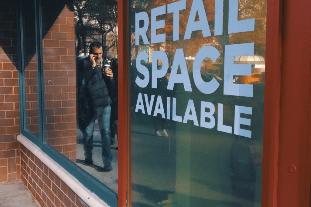 NYC street photography, a man's reflection captured next to a sign stating retail space available - captured with Panasonic S9