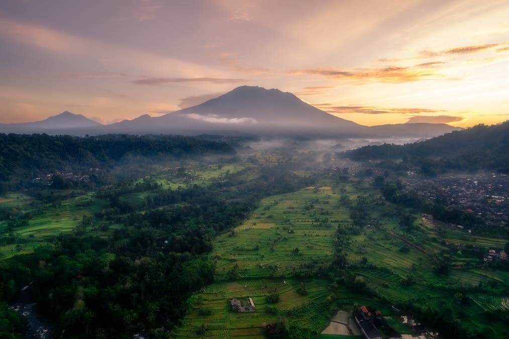 A drone photograph of a sunrise over Mount Agung in Bali, captured using automatic exposure bracketing. The images were later blended and post-processed in Adobe Lightroom.