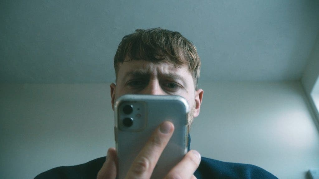 man stares confused at his iPhone