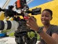 A female videographer smiles while adjusting a professional Sony FX6 cinema camera, which serves as the primary angle in this two-camera setup.