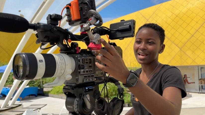 A female videographer smiles while adjusting a professional Sony FX6 cinema camera, which serves as the primary angle in this two-camera setup.