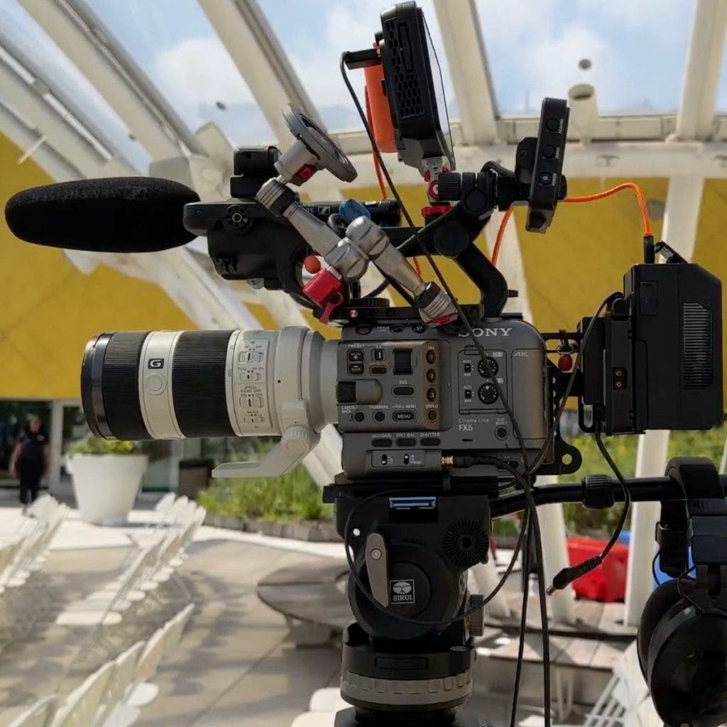 A side profile of a Sony FX6 cinema camera mounted on a Sirui tripod, featuring a telephoto lens and monitor as part of a professional two-camera setup.