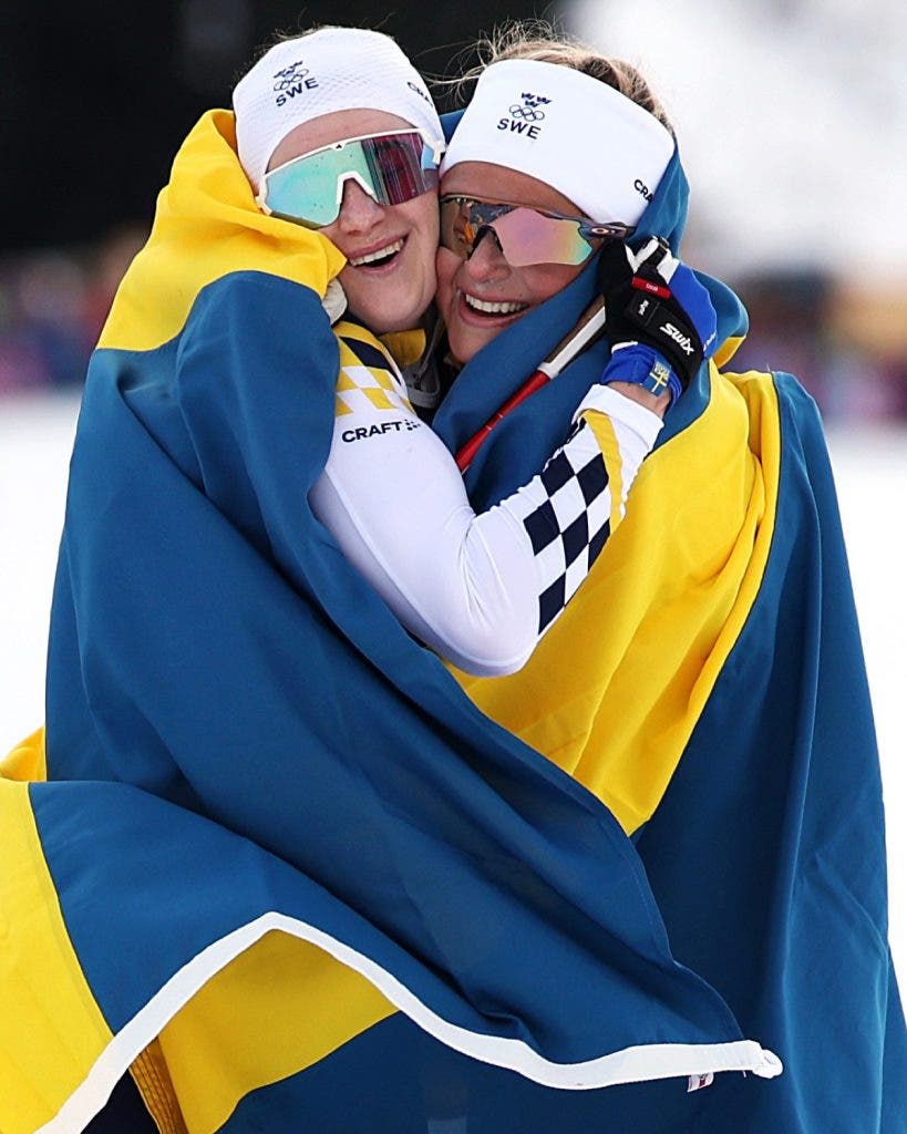 Gold medalist Frida Karlsson of Team Sweden and Silver medalist Ebba Andersson of Team Sweden embrace after competing in the Women's 10km + 10km Skiathlon on day one of the Milano Cortina 2026 Winter Olympic games at Tesero Cross-Country Skiing Stadium on February 07, 2026, in Val di Fiemme, Italy. Photo by Maddie Meyer/Getty Images