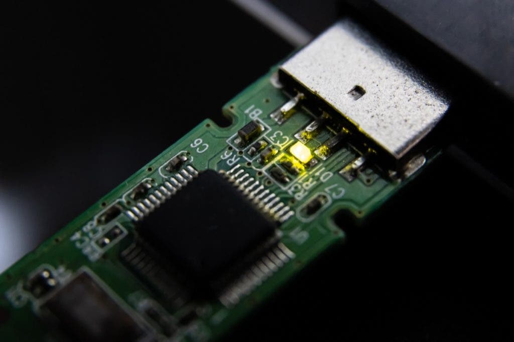 A close-up of a green circuit board with an illuminated yellow LED, representing the active data processing or recovery of a memory module.