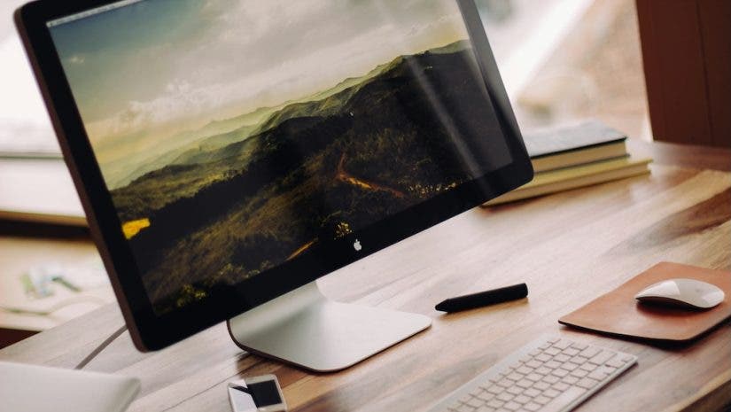 picture of wooden desk with Mac monitor and magic keyboard