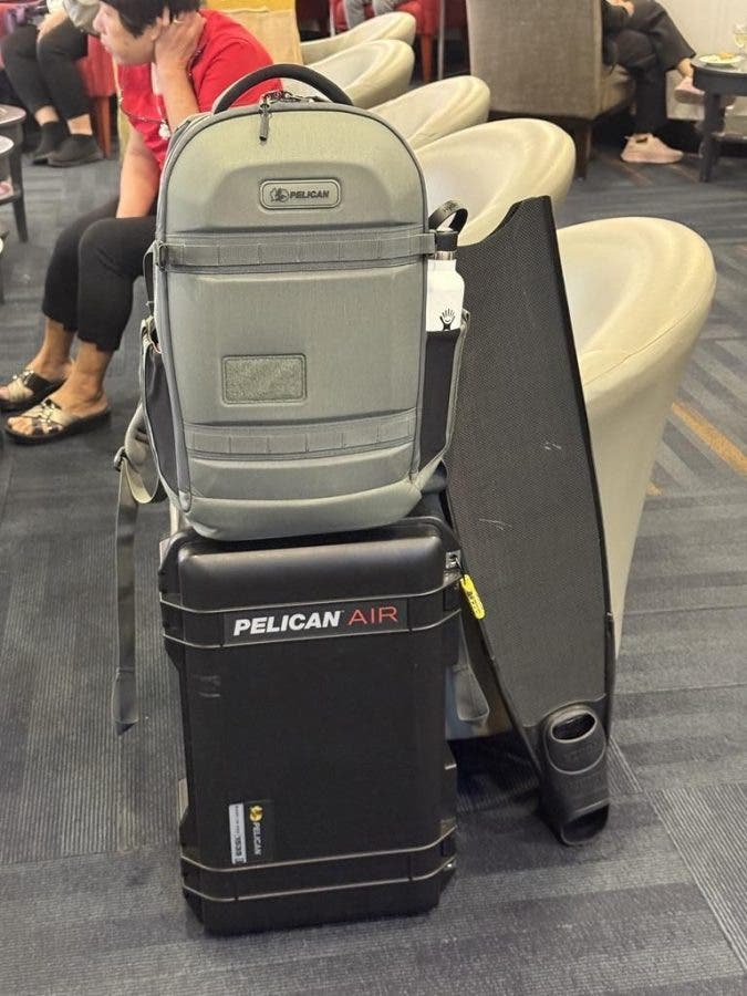 Pelican Air black luggage and grey backpack beside black fins