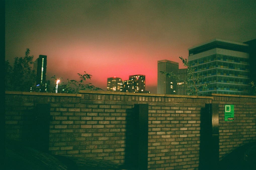 a sunset over a brick wall, skyrise buildings 