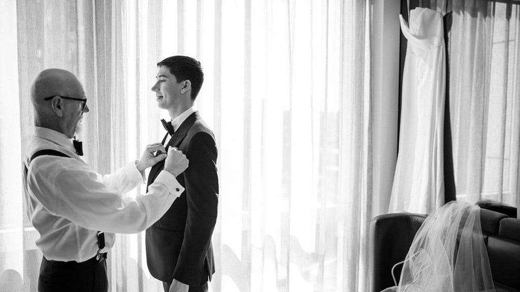 a father helps his son on his wedding day with his suit