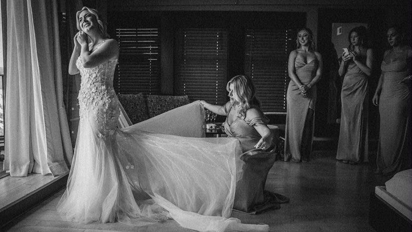 a wedding entourage helps the bride with her dress