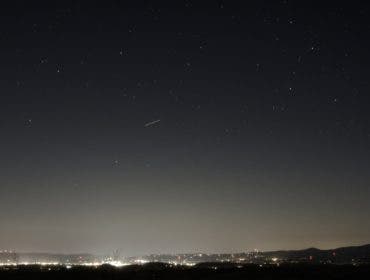 Night sky with stars above a small city showing the light pollution gradient of a Bortle 4/5 location