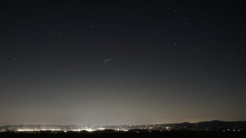 Night sky with stars above a small city showing the light pollution gradient of a Bortle 4/5 location