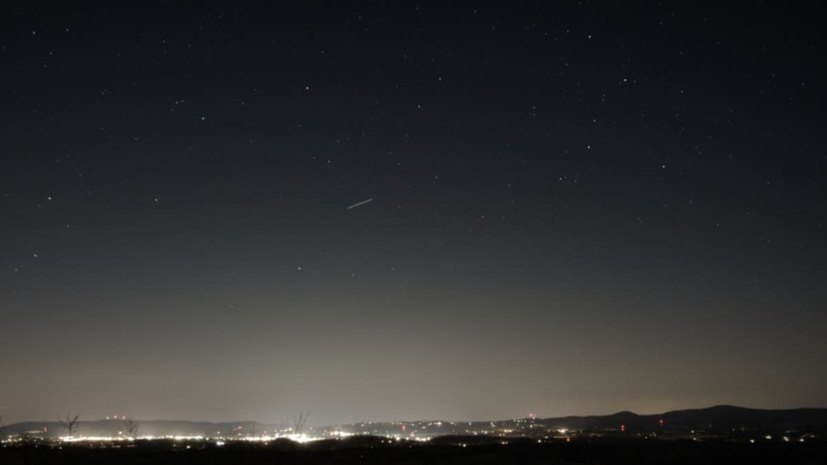 Night sky with stars above a small city showing the light pollution gradient of a Bortle 4/5 location