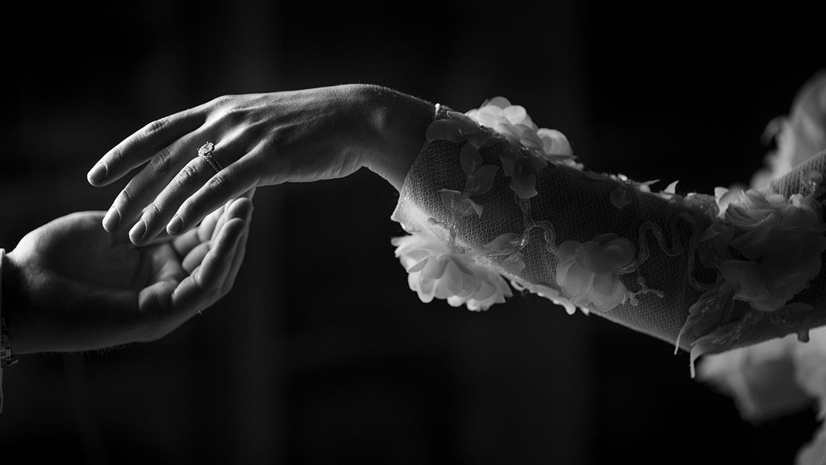 woman wearing wedding dress reaches for husband's hand