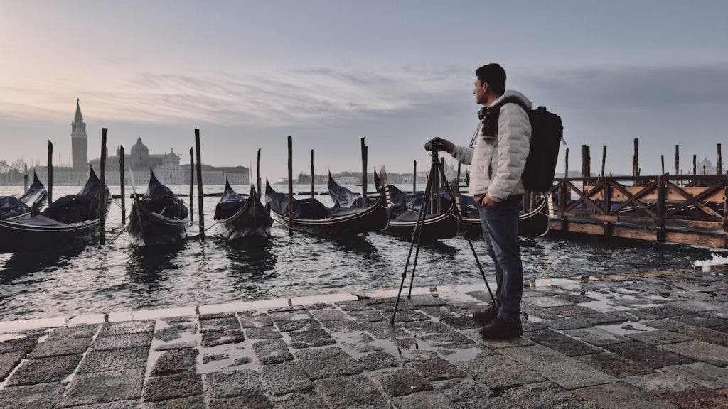 photographer stands with his camera, looking at docked boats