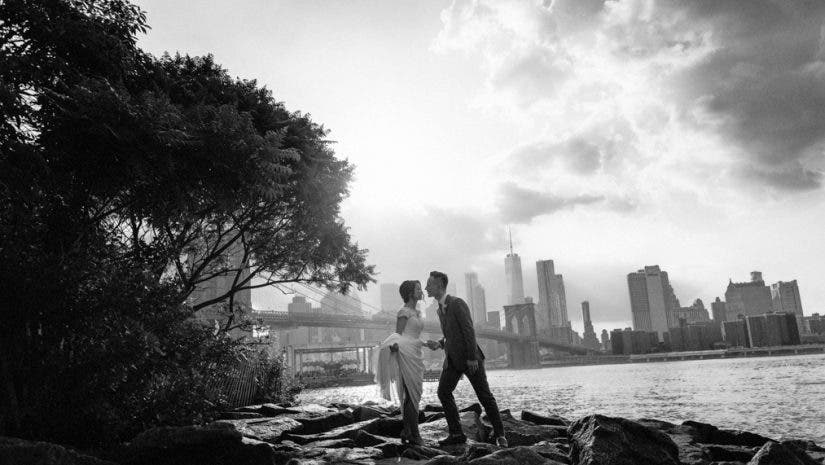 bride holds her dress up as she kisses groom on a rocky riverbank