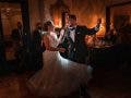 groom in tuxedo and bride in wedding dress happily dance around holding drinks