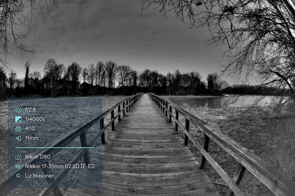 Black and white photo of a boardwalk over a mudflat with EXIF data overlay