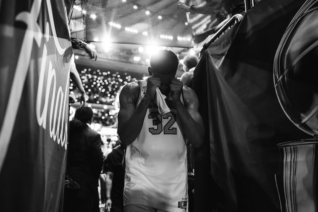 A black-and-white photo of an emotional Karl-Anthony Towns of the New York Knicks walking through the arena tunnel during the NBA Finals