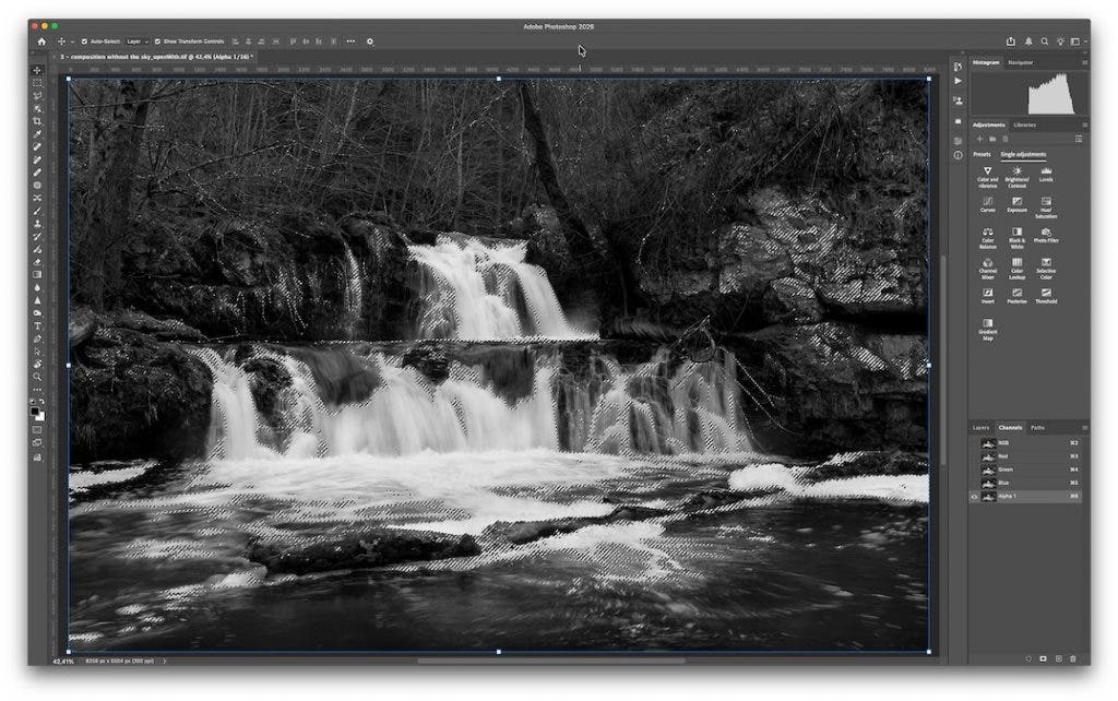 Adobe Photoshop 2026 workspace displaying a black and white image of a rocky stream. A complex "marching ants" selection outline surrounds the brighter areas of the water, indicating an active luminosity mask. The "Alpha 1" channel is selected in the Channels panel on the right