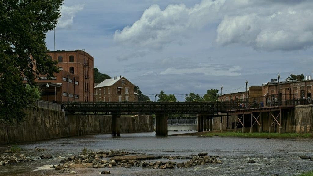 Photo of an urban creek and bridge lined with historic brick buildings, shot on LUMIX G9II