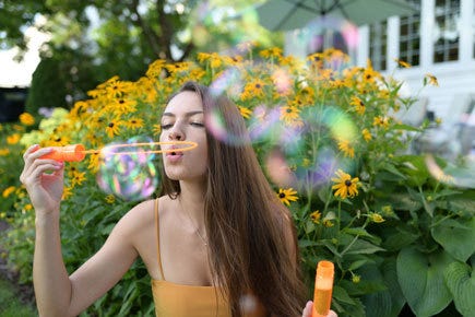 Nikon NIKKOR Z 35mm f/1.8 S Lens 13 outdoor shot of female model blowing bubbles taken with 35mm Z lens